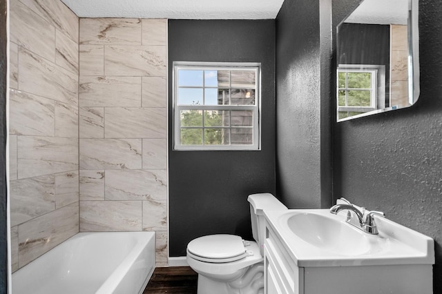 full bathroom with wood finished floors, vanity, toilet, washtub / shower combination, and a textured wall