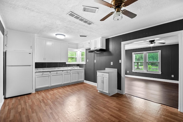 kitchen with white refrigerator, light wood finished floors, a ceiling fan, and light countertops