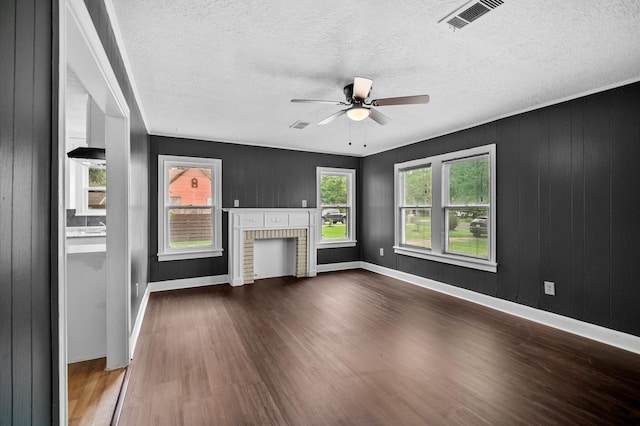 unfurnished living room with a fireplace, a ceiling fan, baseboards, wood finished floors, and visible vents