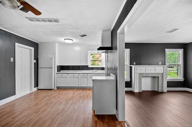 kitchen featuring white cabinets, light countertops, light wood-style flooring, freestanding refrigerator, and a ceiling fan