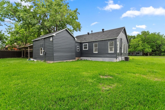 rear view of property featuring a lawn, central AC unit, and roof with shingles