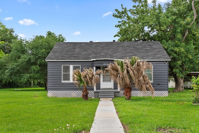 view of front facade with a shingled roof and a front yard