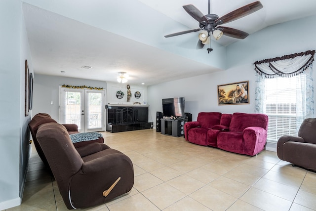 living area featuring a fireplace with raised hearth, ceiling fan, light tile patterned flooring, and vaulted ceiling