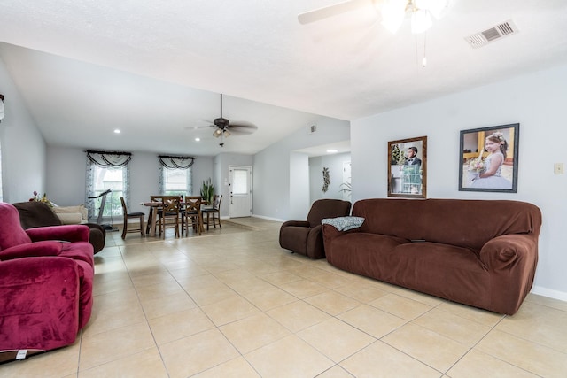 living room featuring visible vents, lofted ceiling, light tile patterned flooring, baseboards, and a ceiling fan