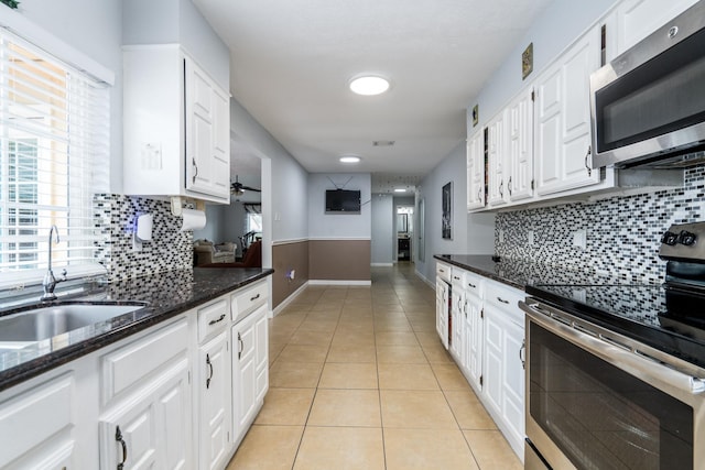 kitchen featuring stainless steel appliances, baseboards, white cabinetry, and a sink