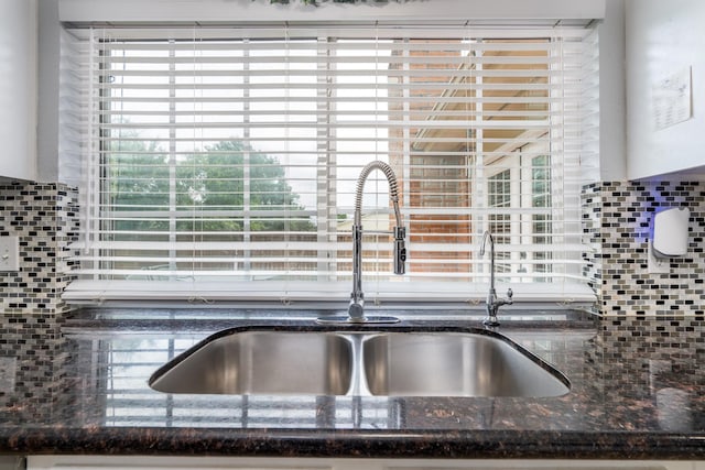 details featuring a sink, dark stone counters, and decorative backsplash