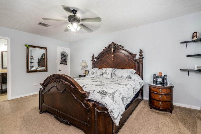bedroom featuring ceiling fan, visible vents, baseboards, ensuite bathroom, and light carpet