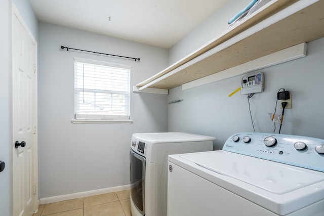 clothes washing area featuring light tile patterned flooring, laundry area, washing machine and dryer, and baseboards