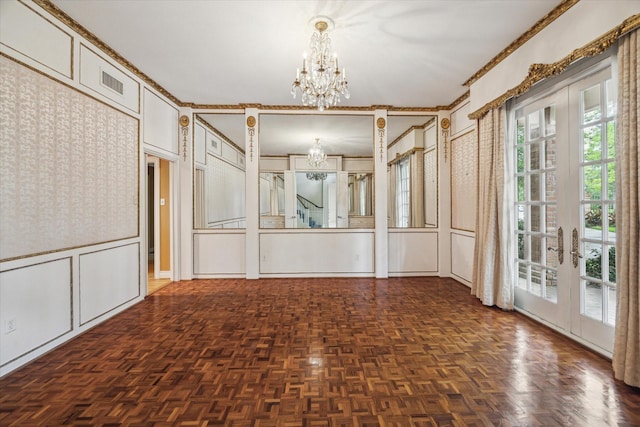 unfurnished room with french doors, ornamental molding, a decorative wall, and a chandelier