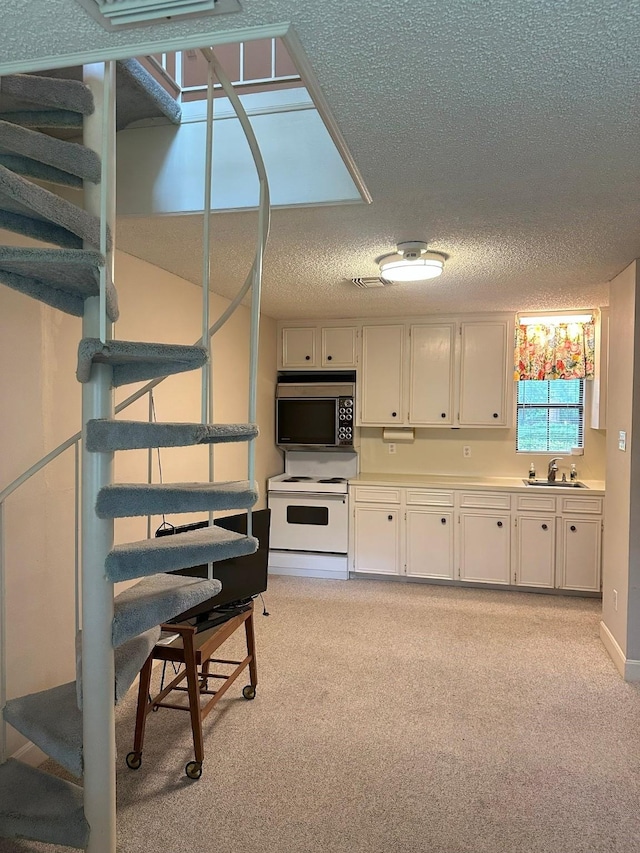 kitchen featuring light carpet, white range with electric cooktop, light countertops, a textured ceiling, and white cabinets
