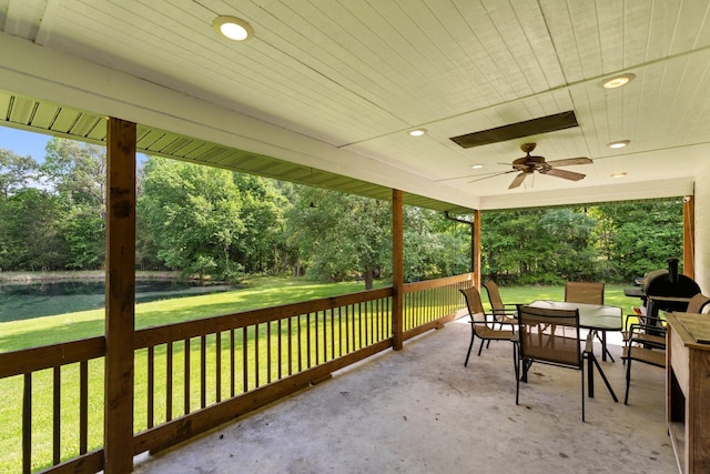 view of patio / terrace with a ceiling fan, a water view, and outdoor dining space