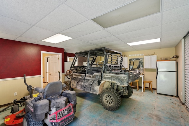 interior space with freestanding refrigerator and a wainscoted wall