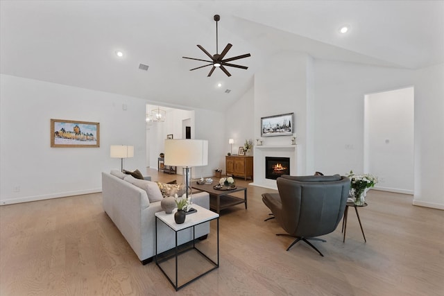 15631 Audubon Park Dr, Magnolia, TX 77354 - living area featuring high vaulted ceiling, ceiling fan, light wood-style flooring, a lit fireplace, and baseboards