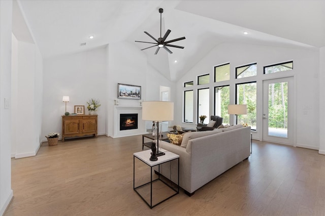 15631 Audubon Park Dr, Magnolia, TX 77354 - living area featuring a glass covered fireplace, a ceiling fan, high vaulted ceiling, light wood-style floors, and baseboards