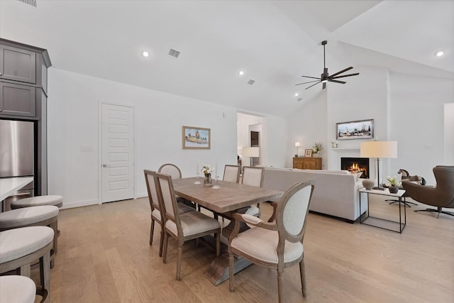 15631 Audubon Park Dr, Magnolia, TX 77354 - dining room with light wood-style flooring, a warm lit fireplace, ceiling fan, high vaulted ceiling, and recessed lighting