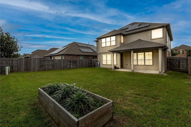 back of property featuring a vegetable garden, solar panels, and a patio