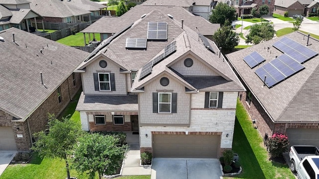 view of front of property with a residential view, stone siding, driveway, roof mounted solar panels, and a garage