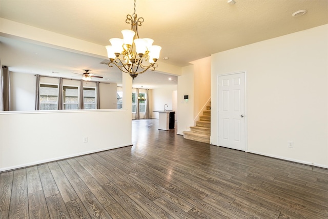 spare room featuring a ceiling fan, a chandelier, dark wood-style flooring, and stairway