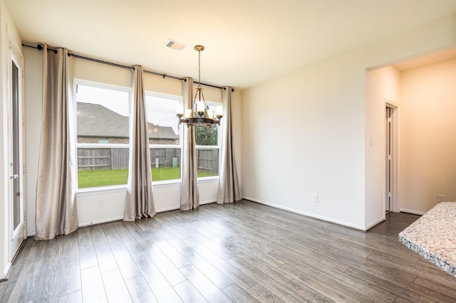 unfurnished dining area with a chandelier, dark wood-style flooring, and baseboards