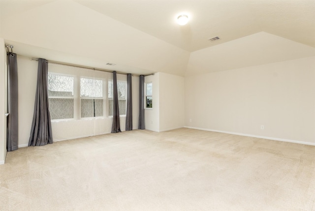 spare room featuring light colored carpet, baseboards, and lofted ceiling