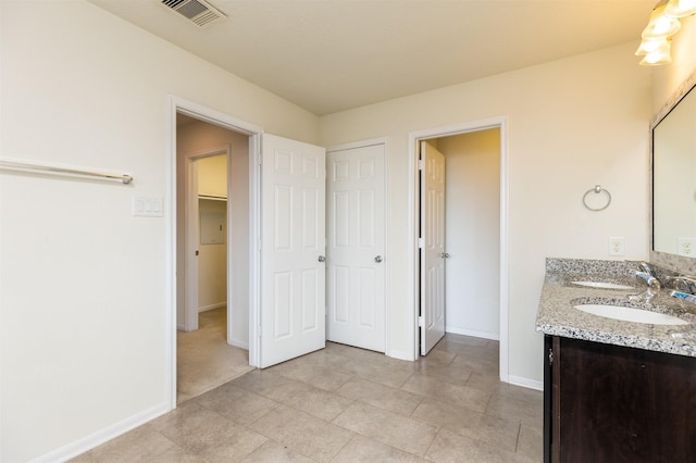 bathroom with baseboards, a closet, double vanity, and tile patterned flooring