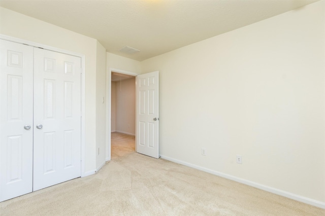 unfurnished bedroom with light colored carpet, baseboards, and a closet
