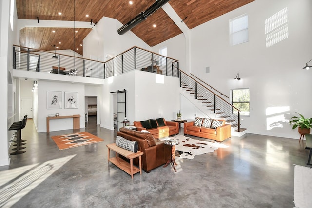 23058 Mills Rd, Porter, TX 77365 - living area with concrete flooring, a barn door, high vaulted ceiling, wooden ceiling, and stairway