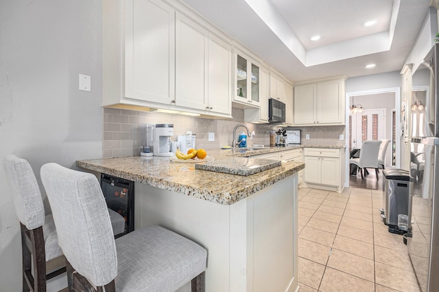 2722 Masters Dr, League City, TX 77573 - kitchen featuring decorative backsplash, a peninsula, black microwave, light stone counters, and a sink