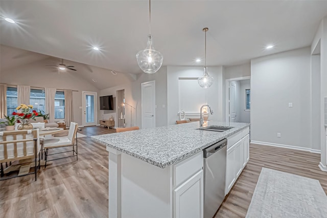 kitchen featuring stainless steel dishwasher, a sink, white cabinets, light wood finished floors, and open floor plan