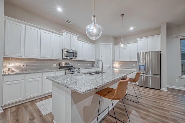 kitchen with visible vents, light wood-type flooring, a sink, appliances with stainless steel finishes, and backsplash