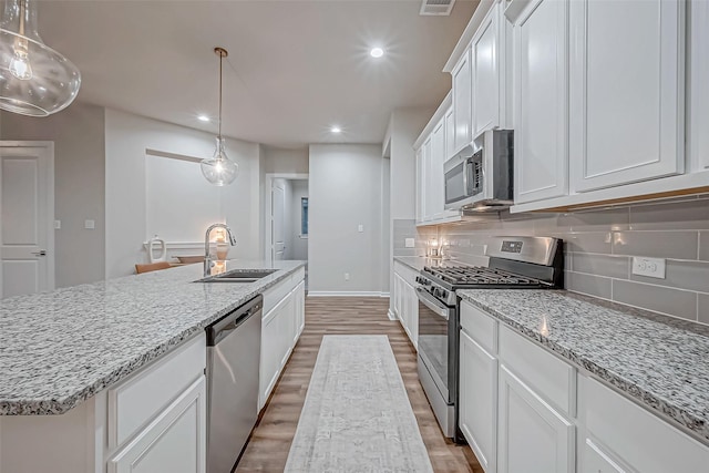 kitchen featuring backsplash, appliances with stainless steel finishes, a sink, light wood finished floors, and recessed lighting