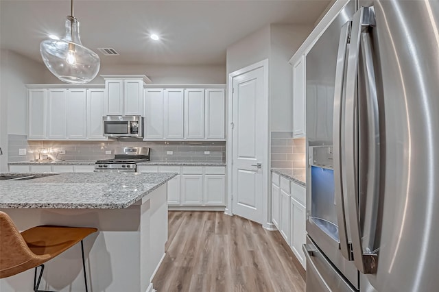 kitchen with decorative backsplash, visible vents, light wood-style floors, stainless steel appliances, and white cabinetry