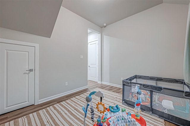 rec room with baseboards, wood finished floors, and vaulted ceiling