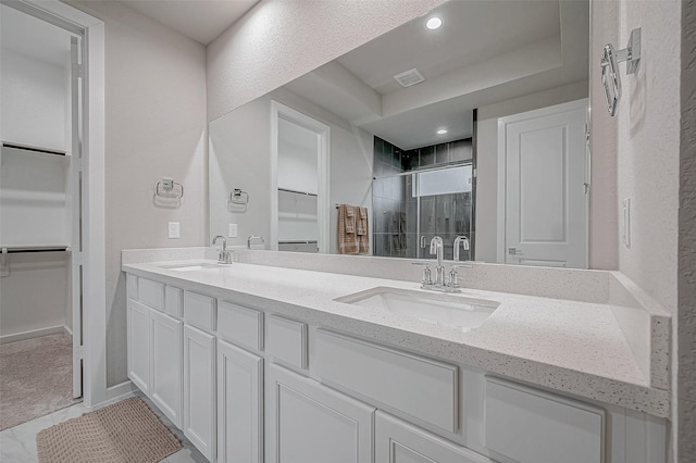 bathroom featuring a walk in closet, visible vents, a shower stall, and a sink