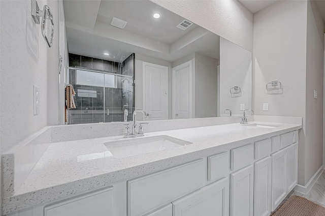 bathroom featuring double vanity, visible vents, a shower stall, and a sink
