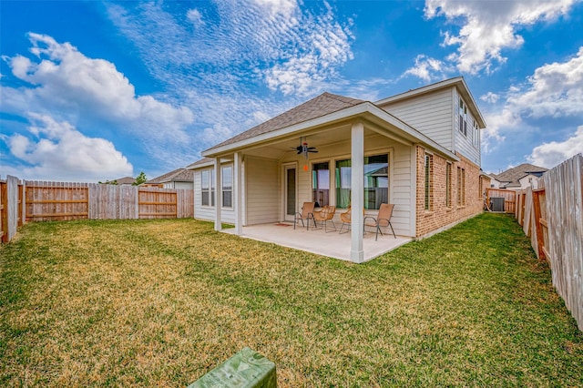 rear view of property with brick siding, a fenced backyard, a patio area, a ceiling fan, and a yard