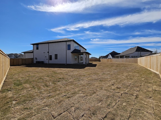 rear view of house featuring a fenced backyard and a lawn