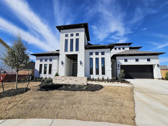 prairie-style house featuring concrete driveway, an attached garage, fence, and stucco siding