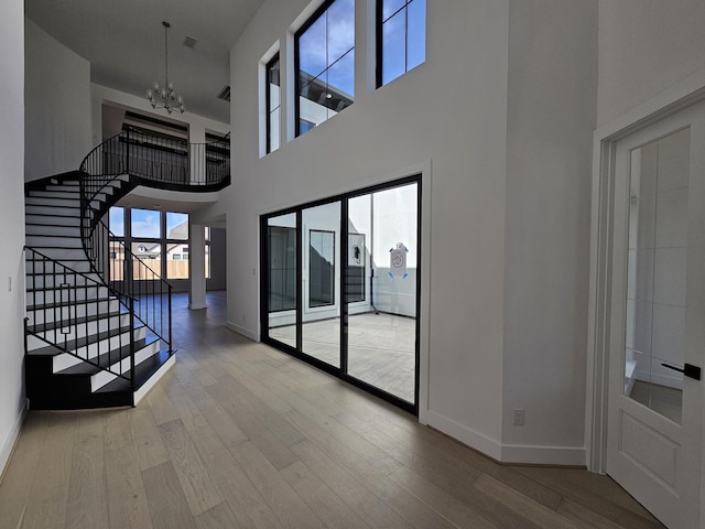 interior space with stairs, baseboards, an inviting chandelier, and wood finished floors