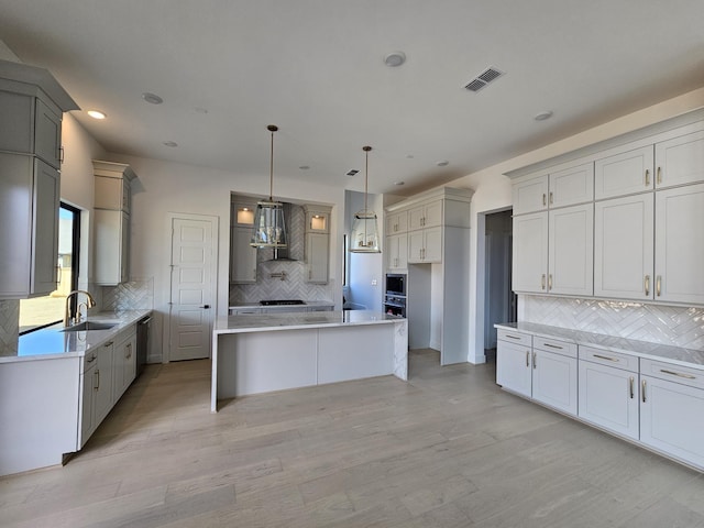 kitchen featuring a sink, gray cabinets, ventilation hood, and tasteful backsplash