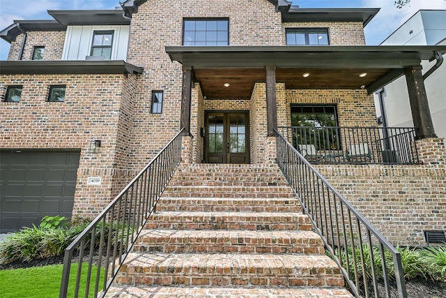 doorway to property with brick siding, a garage, and french doors