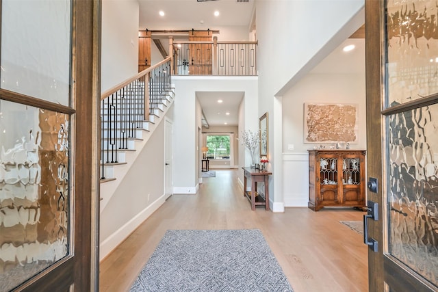 entrance foyer featuring a high ceiling, a barn door, light wood-style flooring, and stairway