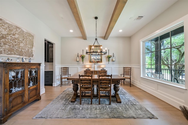 dining area featuring visible vents, wood finished floors, a wainscoted wall, beamed ceiling, and an inviting chandelier