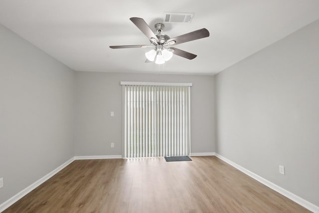 empty room featuring a ceiling fan, baseboards, visible vents, and wood finished floors