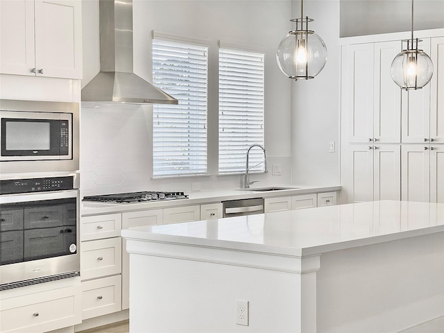 7705 Westside Villas Ln, Houston, TX 77055 - kitchen featuring light countertops, wall chimney exhaust hood, white cabinets, a sink, and stainless steel appliances