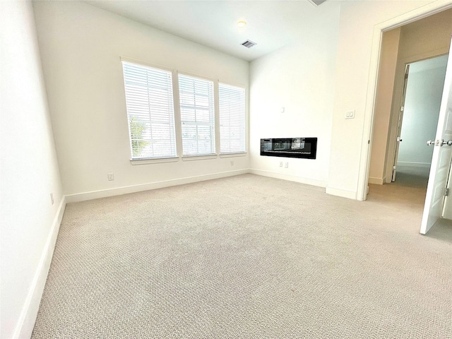 7705 Westside Villas Ln, Houston, TX 77055 - unfurnished living room with baseboards, light carpet, a glass covered fireplace, and visible vents