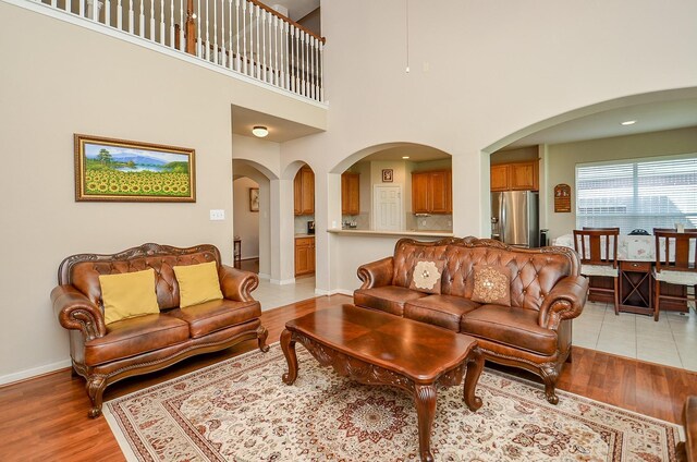 24242 Yelverton Glen Dr, Katy, TX 77493 - living room with light wood-style floors, arched walkways, baseboards, and a towering ceiling