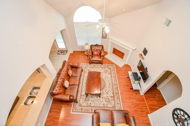 24242 Yelverton Glen Dr, Katy, TX 77493 - living area featuring high vaulted ceiling, a ceiling fan, wood finished floors, a tile fireplace, and visible vents