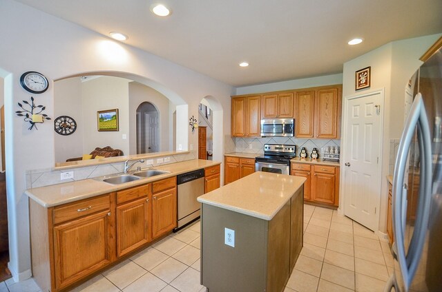 24242 Yelverton Glen Dr, Katy, TX 77493 - kitchen with a sink, light countertops, arched walkways, stainless steel appliances, and decorative backsplash