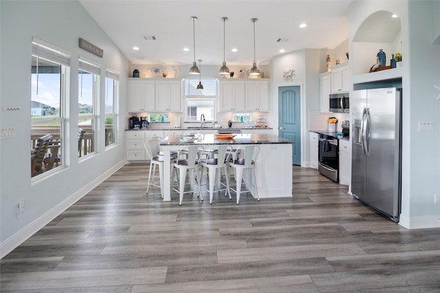 4413 Strand Ave, Port Bolivar, TX 77650 - kitchen with stainless steel appliances, a sink, a kitchen island, white cabinets, and decorative backsplash